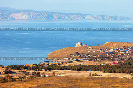 Baikal Lake in autumn. Top view of Small Sea Strait, Khuzhir village, famous Shamanka rock, ship pier, Baikalov Ostrog tourist campsite, wooden village houses, mountains and yellowed steppe meadows (2023 год). Стоковое фото, фотограф Виктория Катьянова / Фотобанк Лори