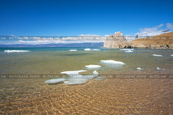 Baikal Lake in spring sunny day. Beautiful landscape with melting ice floes on sandy beach at Khuzhir village of Olkhon Island. View of natural landmark - famous Shamanka Rock. Spring travels and outdoors. Стоковое фото, фотограф Виктория Катьянова / Фотобанк Лори