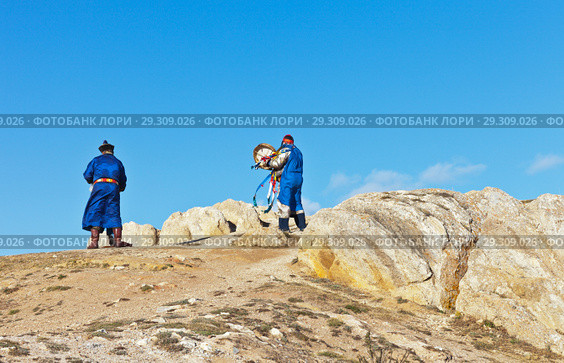 Baikal Lake. Olkhon Island. Shamans in traditional robes with colored ribbons and a tambourine conduct a rite and prayer at Cape Burkhan and bring gifts to local deities (2018 год). Редакционное фото, фотограф Виктория Катьянова / Фотобанк Лори