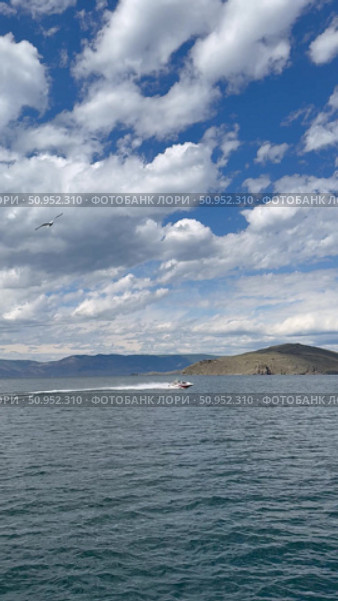 Baikal Lake on summer day. Vertical video of Small Sea Strait and shores of Olkhon Island from ferry board. Motorboat with tourists on blue water. Seagulls in sky with clouds. Стоковое видео, видеограф Виктория Катьянова / Фотобанк Лори
