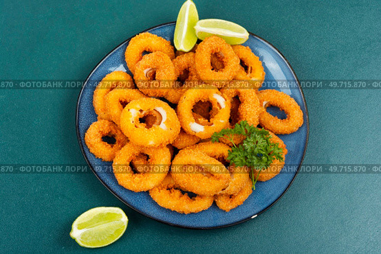Baked breaded calamari rings served with lime. Rings of squid, unhealthy food. Стоковое фото, агентство Ingram Publishing / Фотобанк Лори