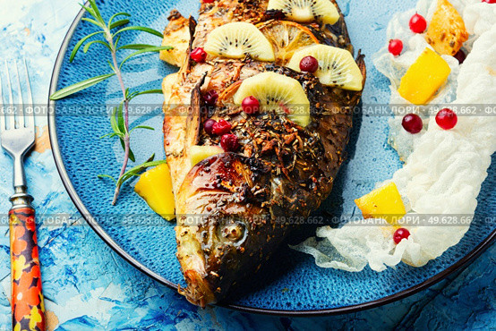 Baked fish carp with fruits, berries and spices.. Tasty crucian fried with kiwi and mango. Стоковое фото, агентство Ingram Publishing / Фотобанк Лори