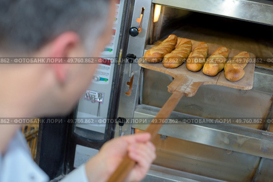baker getting fresh bread out of the traditional oven. Стоковое фото, агентство Ingram Publishing / Фотобанк Лори