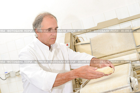 Baker placing dough onto conveyor. Стоковое фото, агентство Ingram Publishing / Фотобанк Лори