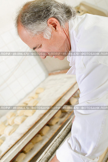 Baker preparing trays of bread rolls. Стоковое фото, агентство Ingram Publishing / Фотобанк Лори