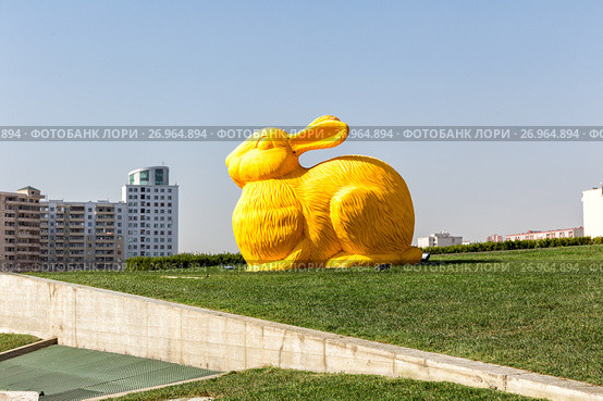 Baku, Azerbaijan - September 24, 2016: Big colorful rabbit on green lawn as elements of landscape design near Heydar Aliyev Center, the building designed by world-famous architect Zaha Hadid. Редакционное фото, фотограф Евгений Ткачёв / Фотобанк Лори