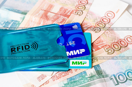 Банковские карты платёжной системы МИР в RFID защитных чехлах  - защита от считывания, мошенничества, кражи - на фоне пятитысячных купюр. Редакционное фото, фотограф Snezka / Фотобанк Лори