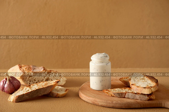 Баночка вкусного соуса Цезарь и багет на бежевом фоне. Стоковое фото, фотограф Pixel_shot / Фотобанк Лори