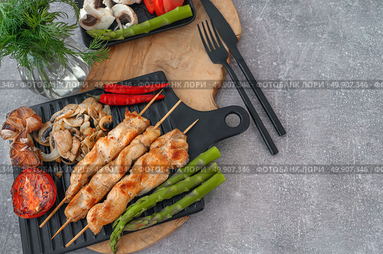 Barbecue on bamboo sticks. Grilled chicken kebab with mushrooms, asparagus and tomato. Red hot kebab. Top view, copy space. Стоковое фото, фотограф Оксана Медведева / Фотобанк Лори