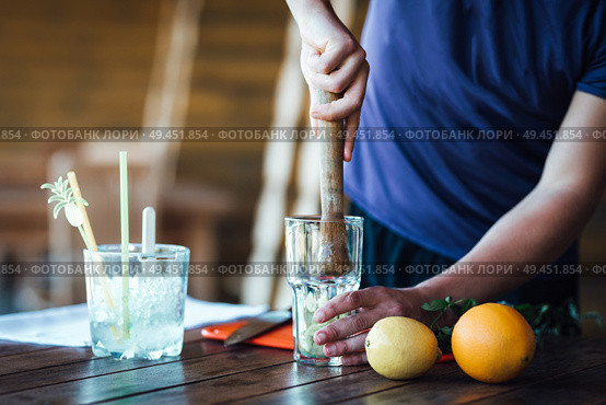 Barman prepares fruit alcohol cocktail based on lime, mint, orange, soda and alcohol. Стоковое фото, агентство Ingram Publishing / Фотобанк Лори
