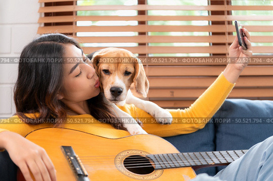 Beagle dog joining the owner’s selfie on the sofa in the living room of the house. Стоковое фото, агентство Ingram Publishing / Фотобанк Лори