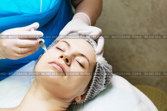 Beautician performs a needle mesotherapy treatment on a woman face. Стоковое фото, фотограф Nataliia Zhekova / Фотобанк Лори