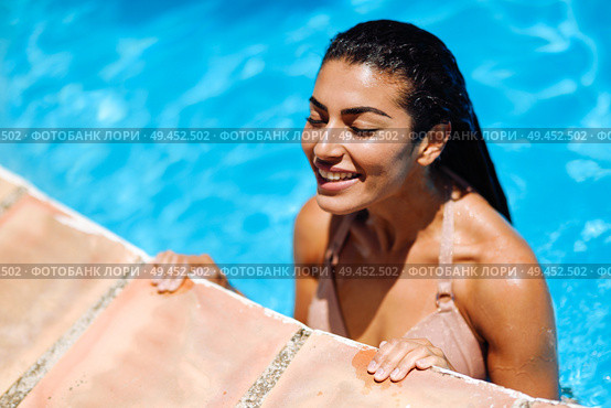 Beautiful Arab woman relaxing in swimming pool with eyes closed. Girl with healthy tanned skin and wet hair enjoying Summer Sun.. Beautiful Arab woman relaxing in swimming pool. . Стоковое фото, агентство Ingram Publishing / Фотобанк Лори