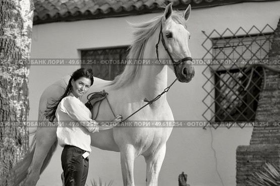beautiful brunette posing with beautiful white Andalusian stallion nearly stable. Spain, Andalusia. Стоковое фото, агентство Ingram Publishing / Фотобанк Лори