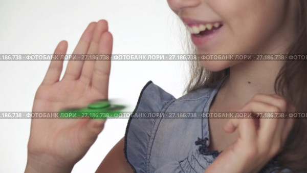 Beautiful cheerful teen girl playing with green fidget spinner on white background stock footage video. Стоковое видео, видеограф Юлия Машкова / Фотобанк Лори