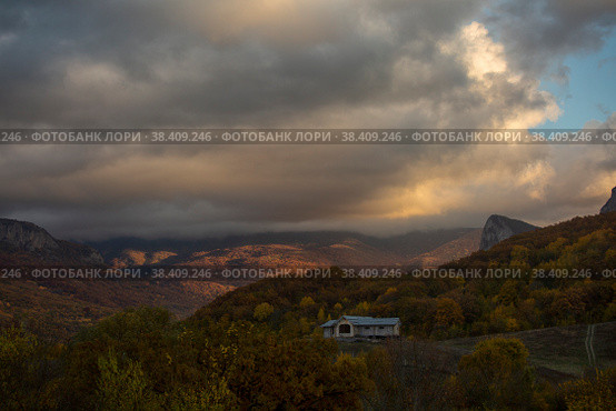 Beautiful clouds in the evening sky over a mountain valley and a wooden house on a hill. Стоковое фото, фотограф Яна Королёва / Фотобанк Лори