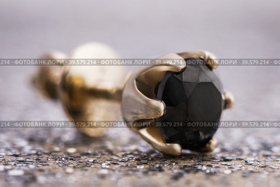 Beautiful gold earrings with a black diamond on the table, close-up (2019 год). Редакционное фото, фотограф Сергей Чайко / Фотобанк Лори