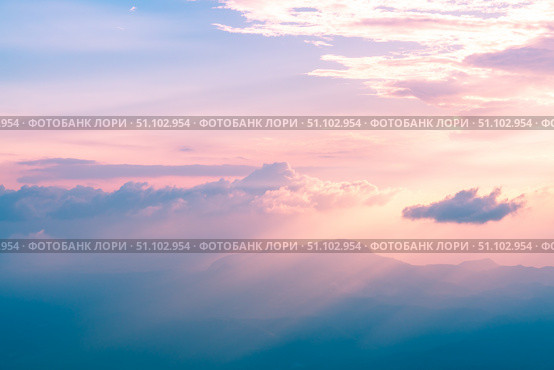 Beautiful pastel-colored sunset illuminating majestic mountain peaks through a layer of clouds, creating a breathtaking and serene natural landscape. Стоковое фото, фотограф Ольга Ильина / Фотобанк Лори