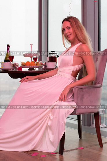 Beautiful slim blonde in a long white with a pink tint from the lighting of the dress at a party. Стоковое фото, фотограф katalinks / Фотобанк Лори