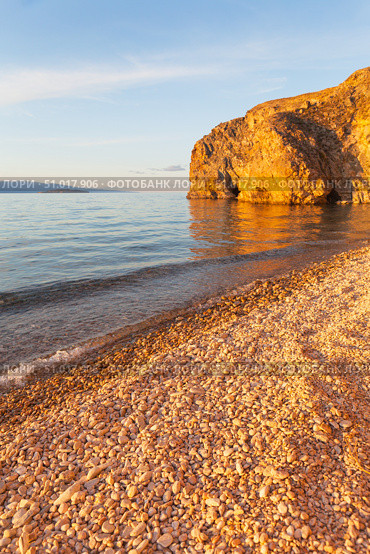 Beautiful sunset landscape of Baikal Lake. View of pebble beach of Small Sea and rocky coast of Olkhon Island on quiet August evening. Picturesque seascape. Natural background. Summer travels. Стоковое фото, фотограф Виктория Катьянова / Фотобанк Лори