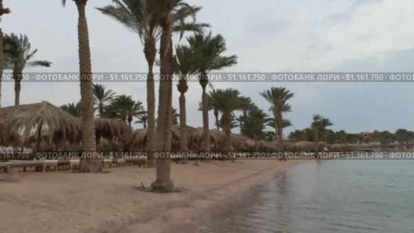 Beautiful tropical sunset scenery, two sun beds, loungers, umbrella under palm tree. White sand, sea view with horizon, colorful twilight sky, calmness and relaxation. Inspirational beach resort hotel. Стоковое видео, видеограф Zita Khasanova / Фотобанк Лори