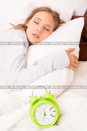 Beautiful woman sleeping with alarmclock on the bed . Стоковое фото, агентство Ingram Publishing / Фотобанк Лори