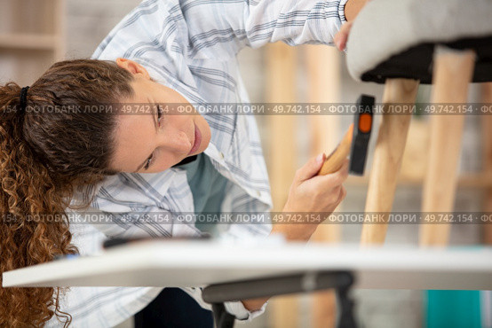 beautiful young woman repairing a chair. Стоковое фото, агентство Ingram Publishing / Фотобанк Лори