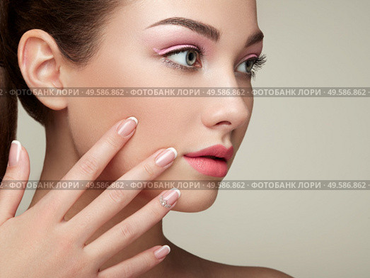 Beauty brunette woman with perfect makeup. Pink lips and nails. Perfect eyebrows. Skin care foundation. Beauty girls face isolated on beige background. Hands with beautiful elegant manicure. Стоковое фото, агентство Ingram Publishing / Фотобанк Лори