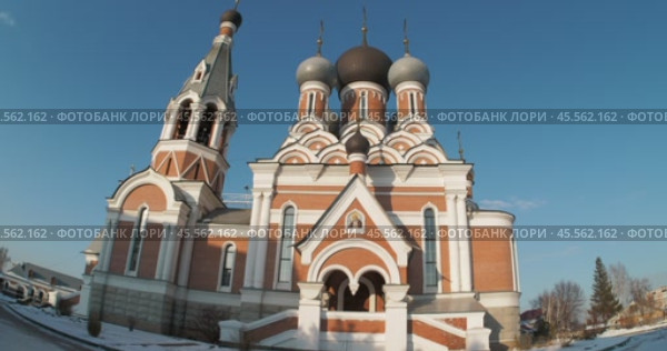 Berdsk, Russia-November, 30,2024. Religion, architecture. The Orthodox Cathedral in honor of the Transfiguration of the Lord, around which there is snow on a background of blue sky. Distortion. Siberia. Редакционное видео, видеограф Сергей Медведев / Фотобанк Лори