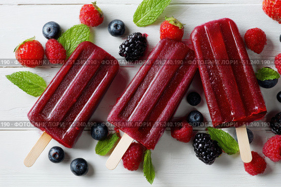 Berry juice popsicles in a plate on a white wooden table with fresh berries. Bright Ice pops with mint leaves and raspberries. Gut-health red pink berry popsicles. Inviting summer scene. Frozen treats. Стоковое AI-изображение, AI-художник Марина Демидюк / Фотобанк Лори