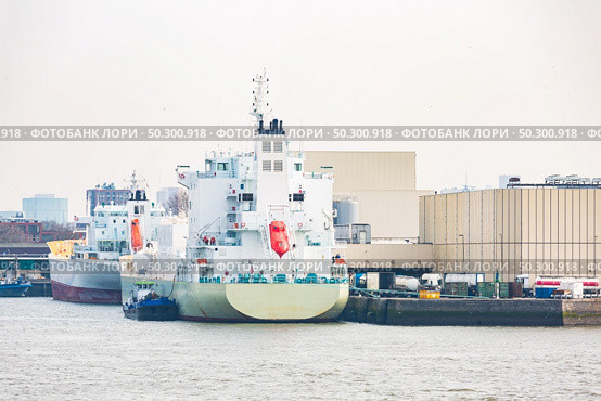 Big Cargo Containers Boat with Goods cargo Stack at the Pier docks port waiting for international sea freight transportation in Rotterdam Port of Netherlands. Стоковое фото, агентство Ingram Publishing / Фотобанк Лори