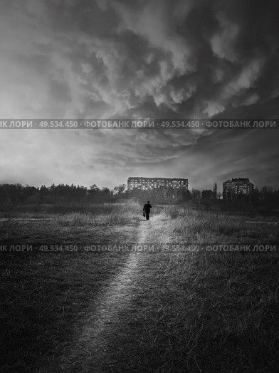 Black and white scene, vertical shot of a wanderer man silhouette walking narrow pathway throw the wilderness. Silent evening atmosphere, dramatic landscape, loneliness and solitude concept. Стоковое фото, агентство Ingram Publishing / Фотобанк Лори