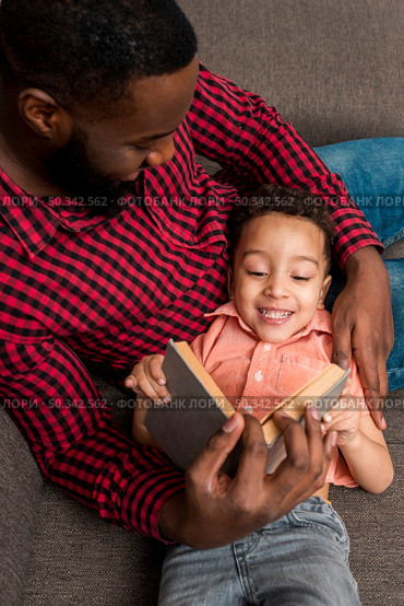 black father cute son reading book couch. Стоковое фото, агентство Ingram Publishing / Фотобанк Лори