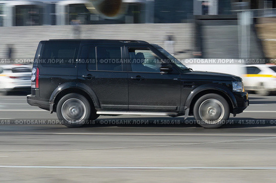 Black offroad car Land Rover Discovery rides in the city street. Side view of SUV car in motion on the road. Compliance with speed limits on the road. Редакционное фото, фотограф Константин Григорьев / Фотобанк Лори