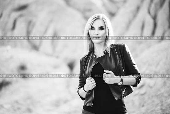 blonde girl in a black trouser suit with blue eyes on the background of a granite quarry from gray rubble. Стоковое фото, агентство Ingram Publishing / Фотобанк Лори