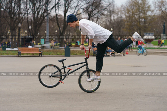 BMX in the Moscow park. Young man doing trick on the bike in the spring day. Extreme sports is very popular among youth. 2019. Редакционное фото, фотограф YuryKara / Фотобанк Лори