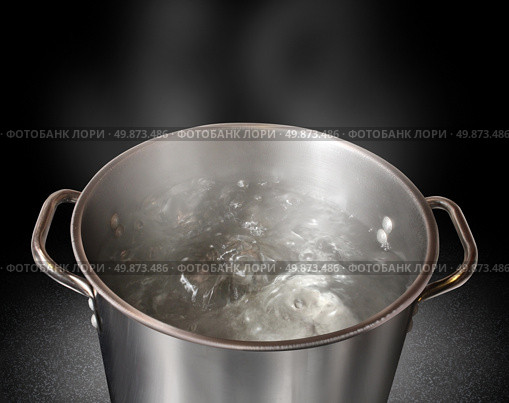 Boiling water in a kitchen pot as a symbol of cooking or food preparation and sterilization of contaminated tap water for healthy pure drinking liquid on a black background. Стоковое фото, агентство Ingram Publishing / Фотобанк Лори
