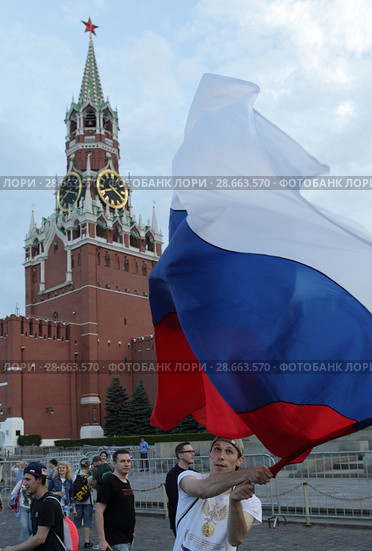 Болельщик Российской сборной с флагом страны на фоне Кремлевских курантов (2018 год). Редакционное фото, фотограф Дмитрий Неумоин / Фотобанк Лори