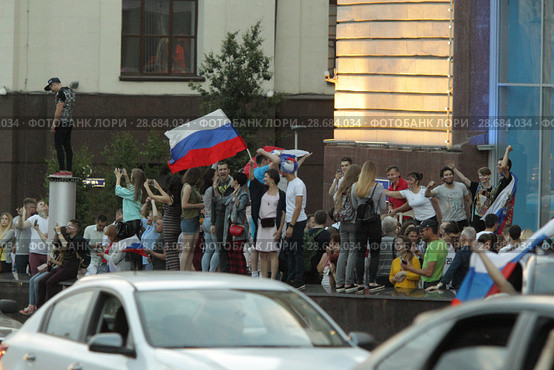 Болельщики сборной России после матча Россия-Испания размахивают флагами из автомобиля на Лубянке (2018 год). Редакционное фото, фотограф Дмитрий Неумоин / Фотобанк Лори