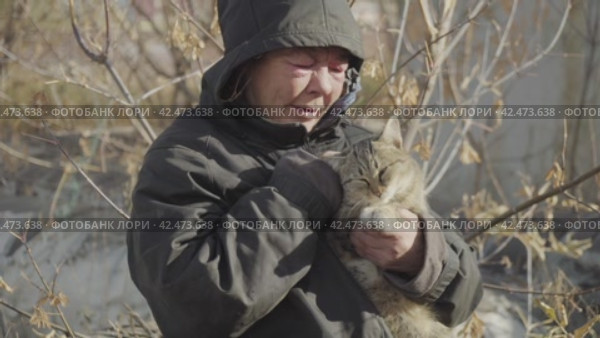 Бомж, бездомная женщина бродяга. Homeless woman vagabond in a temporary place caressing a wandering cat. Стоковое видео, видеограф EStarodubov / Фотобанк Лори