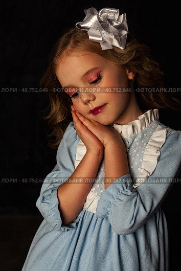 Bored lovely little doll cover girl in blue dress at black background, pensive closed eyes. Darling child of image isolated with light and shadow, studio shot. Fashion style kid concept. Copy ad space. Стоковое фото, фотограф Aleksandr Golubev / Фотобанк Лори