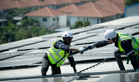 Both of Engineer in charge of solar panel installation The installation of solar energy conversion into electricity for a warehouse is currently being investigated. Стоковое фото, агентство Ingram Publishing / Фотобанк Лори