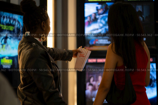 Both of young woman stand and watch the movie program to watch today. Стоковое фото, агентство Ingram Publishing / Фотобанк Лори
