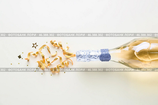 Bottle of champagne and glitters on white background. New year celebration. Стоковое фото, фотограф Pixel_shot / Фотобанк Лори
