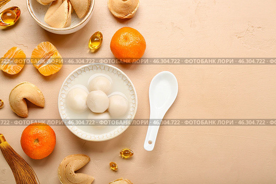 Bowl of tangyuan with fortune cookies and mandarins on beige background. Dongzhi Festival. Стоковое фото, фотограф Pixel_shot / Фотобанк Лори