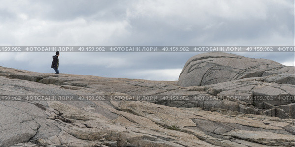 Boy walking at rocky coast, Peggy's Cove, Nova Scotia, Canada. Стоковое фото, агентство Ingram Publishing / Фотобанк Лори
