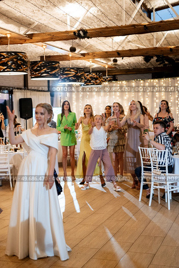 bride in a white dress throws a wedding bouquet to her unmarried girlfriends. Стоковое фото, агентство Ingram Publishing / Фотобанк Лори