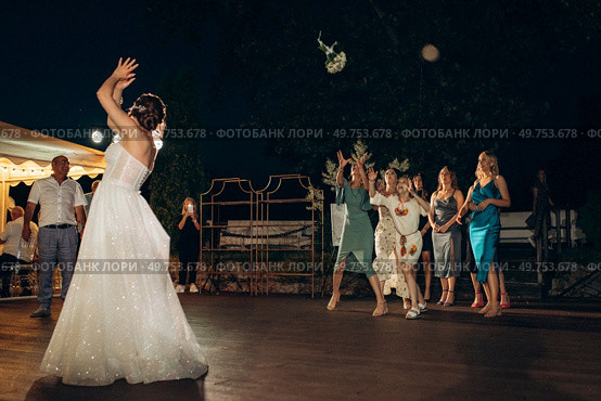 bride in a white dress throws a wedding bouquet to her unmarried girlfriends. Стоковое фото, агентство Ingram Publishing / Фотобанк Лори