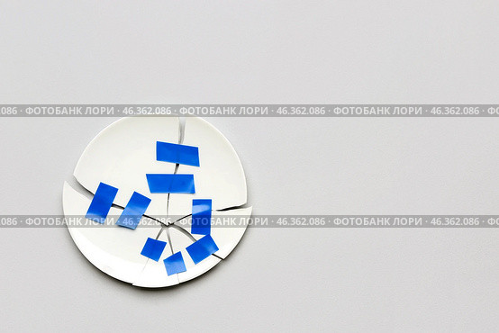 Broken plate with adhesive tape on light background. Стоковое фото, фотограф Pixel_shot / Фотобанк Лори