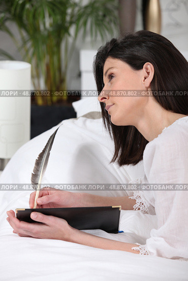 brunet woman  lying on sofa  quill in hand. Стоковое фото, агентство Ingram Publishing / Фотобанк Лори
